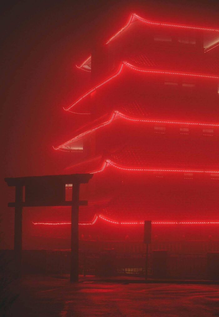 A multi-tiered building outlined in red lights shrouded in mist, exuding an evil aura like a supervillain headquarters.