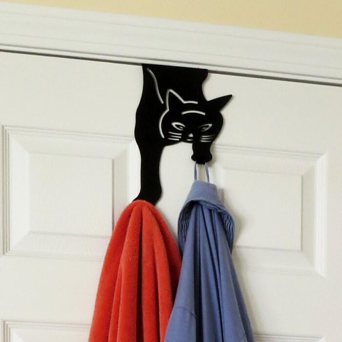 Black cat-shaped door hook holding colorful clothes, a creative and fun white elephant present idea for gift exchanges.
