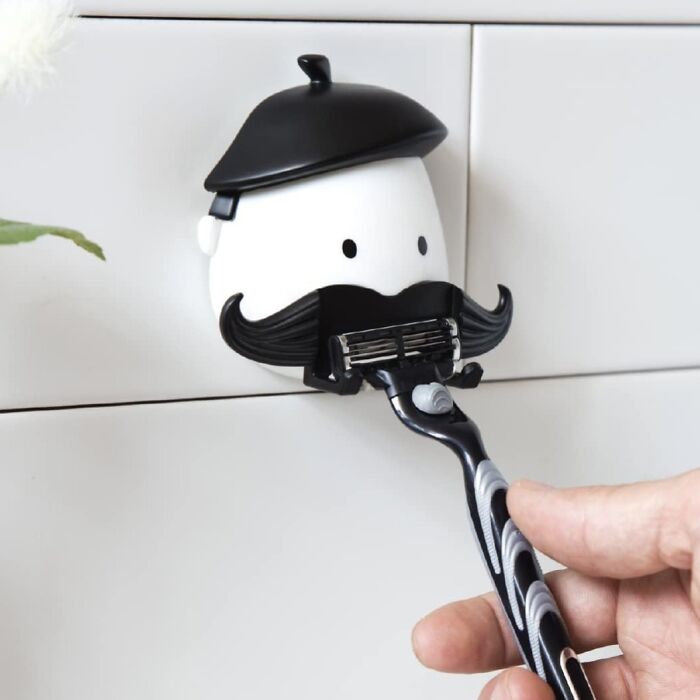 Wall-mounted razor holder with a whimsical mustache design for white elephant gifts.