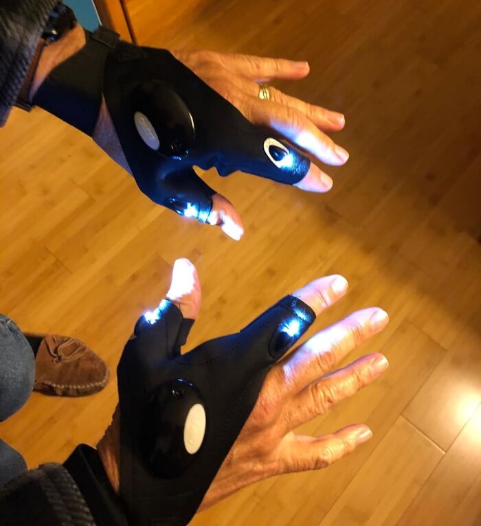 Hands wearing black gloves with built-in LED lights on fingers, a unique white elephant presents idea tempting to keep.