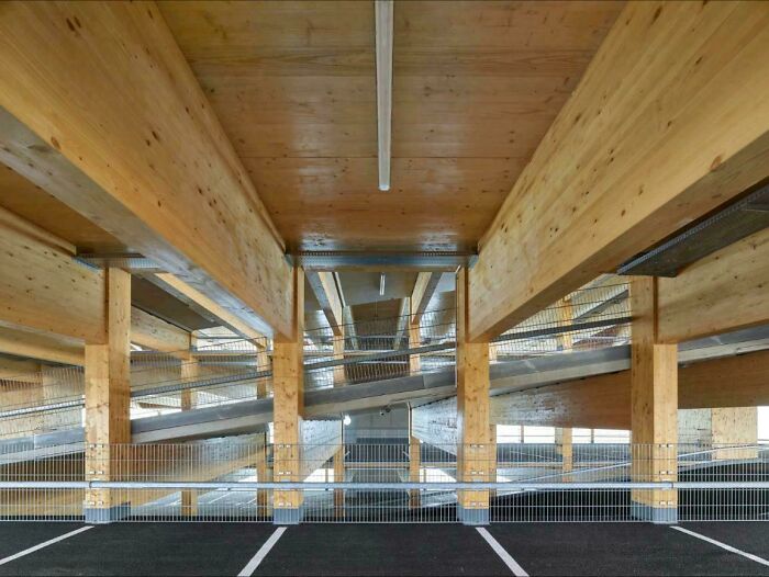 Wooden structural beams and metal railings forming innovative infrastructure in a modern parking garage design.