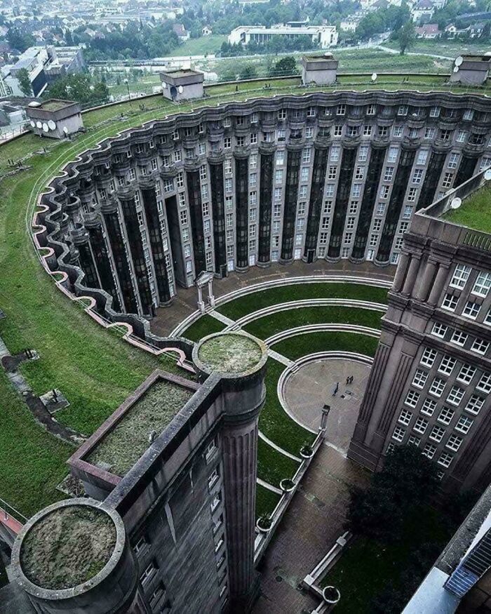 Aerial view of a massive circular building with columns and green rooftops illustrating large scale and megalophobia.
