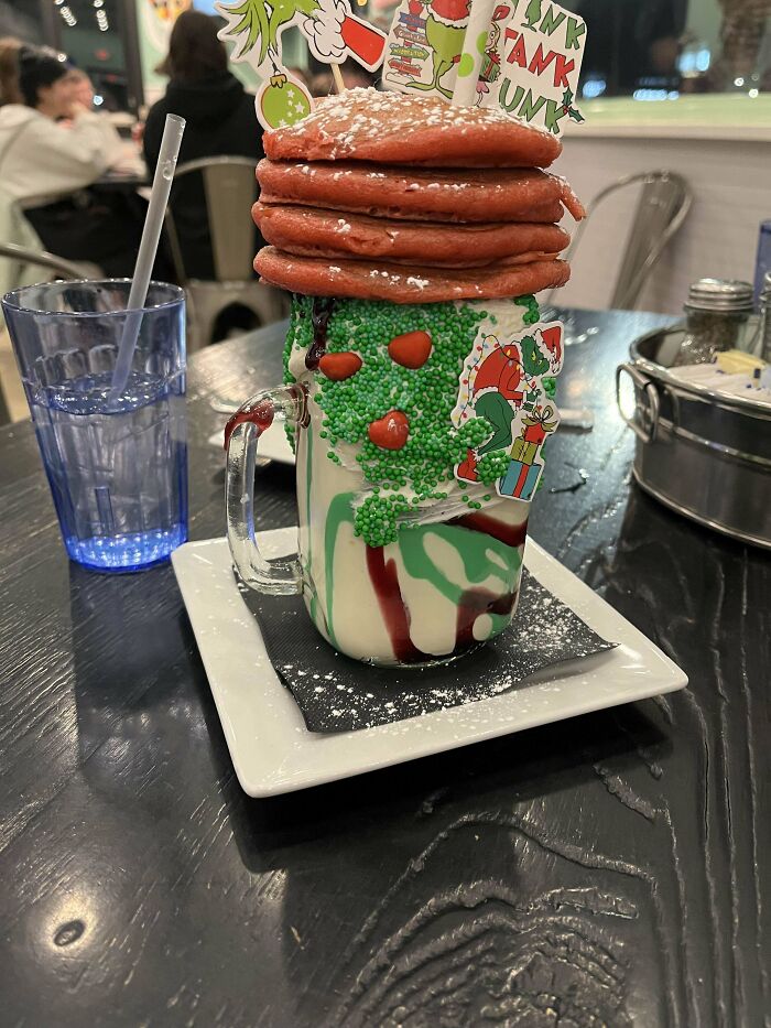 Tall milkshake topped with red pancakes and green sprinkles, an example of dishes that are just stupid and over-the-top.