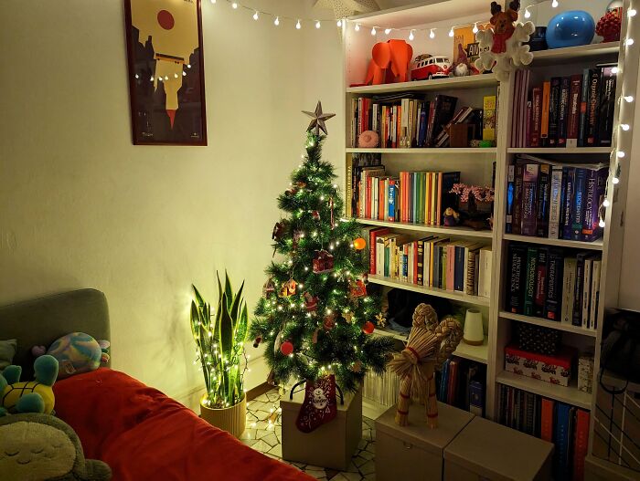 Cozy living room with a decorated Christmas tree, bookshelves, and warm lights, creating a wholesome Christmas atmosphere.