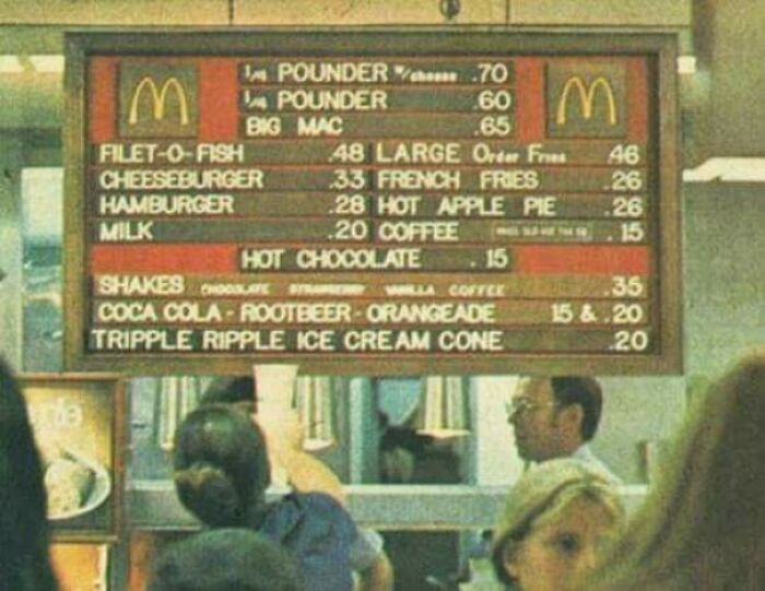 1973 McDonald's menu board with vintage prices and people waiting in line.