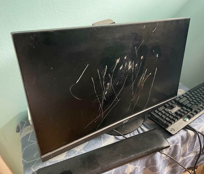 Scratched computer monitor and keyboard, possibly caused by infuriating family members.