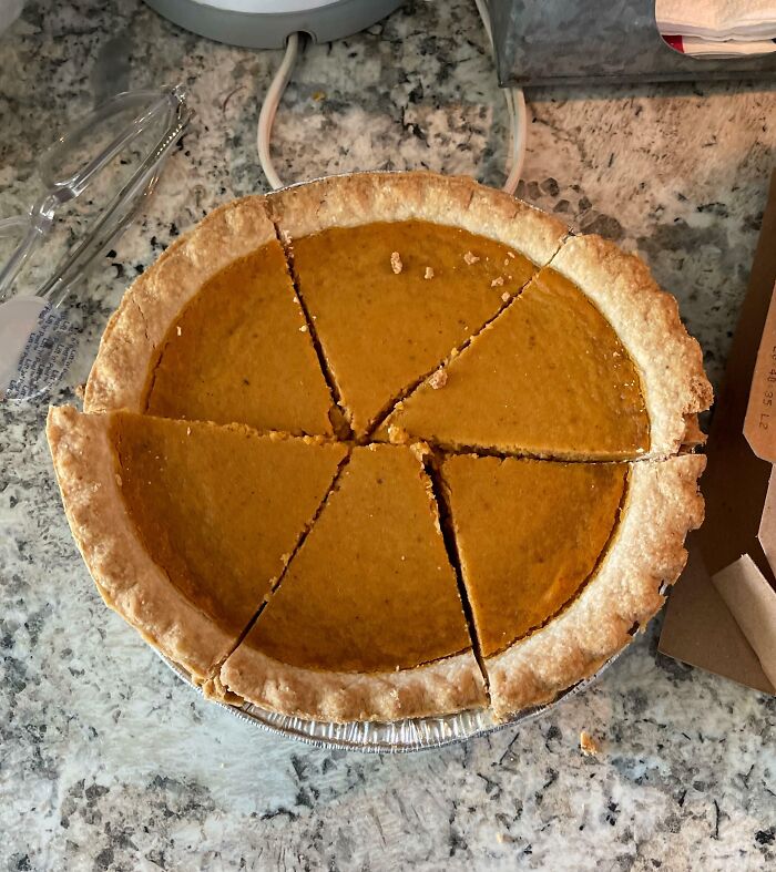 Pumpkin pie unevenly sliced, possibly by infuriating family members, on a granite countertop.