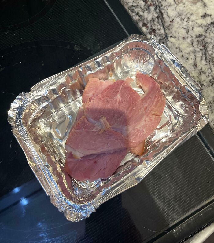Ham left in a foil container on a kitchen countertop, illustrating infuriating family members' cooking habits.