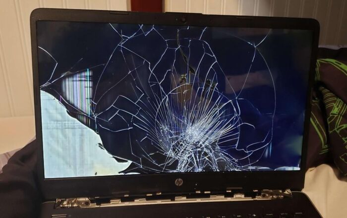 A broken laptop screen, possibly damaged by infuriating family members, with cracks spreading across the display.