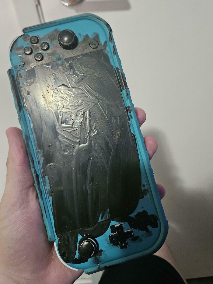 Hand holding a gaming console with paint smeared on it, causing frustration with infuriating family members.