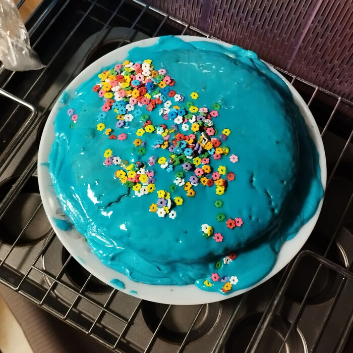 Blue cake with colorful flower sprinkles, showcasing creative baking.