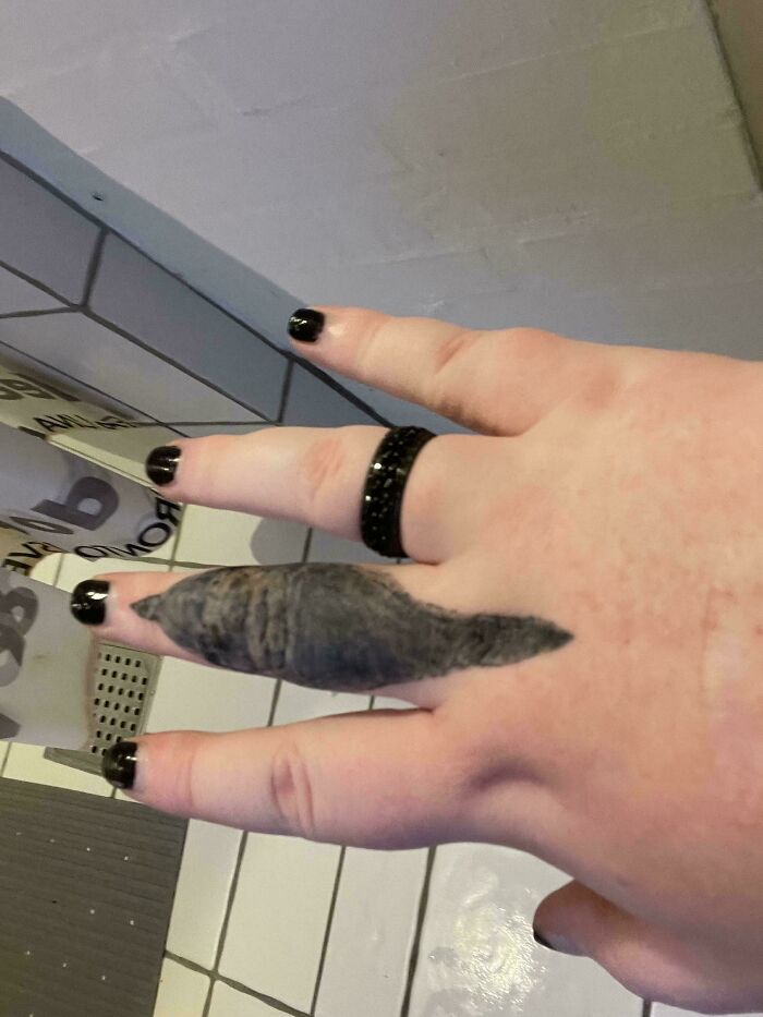 A tattoo resembling a cigar on a finger, highlighting a humorous tattoo fail.