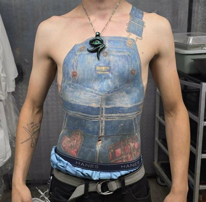 Man with a hyper-realistic denim overalls tattoo across his chest and stomach, showcasing unique tattoo art.