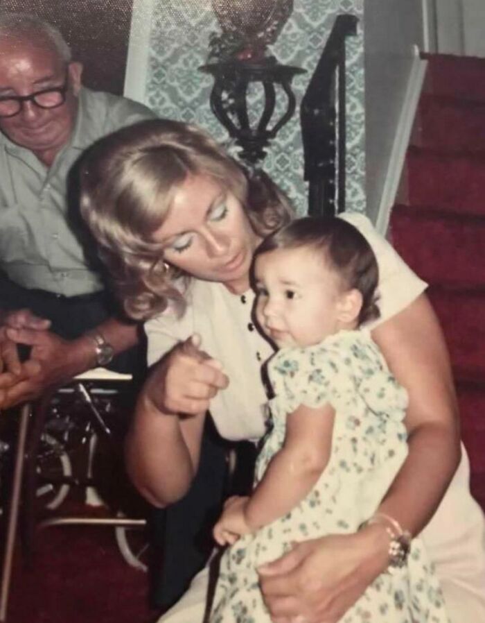 A woman and a child in a vintage 1973 setting with a man in the background, evoking nostalgic family memories.