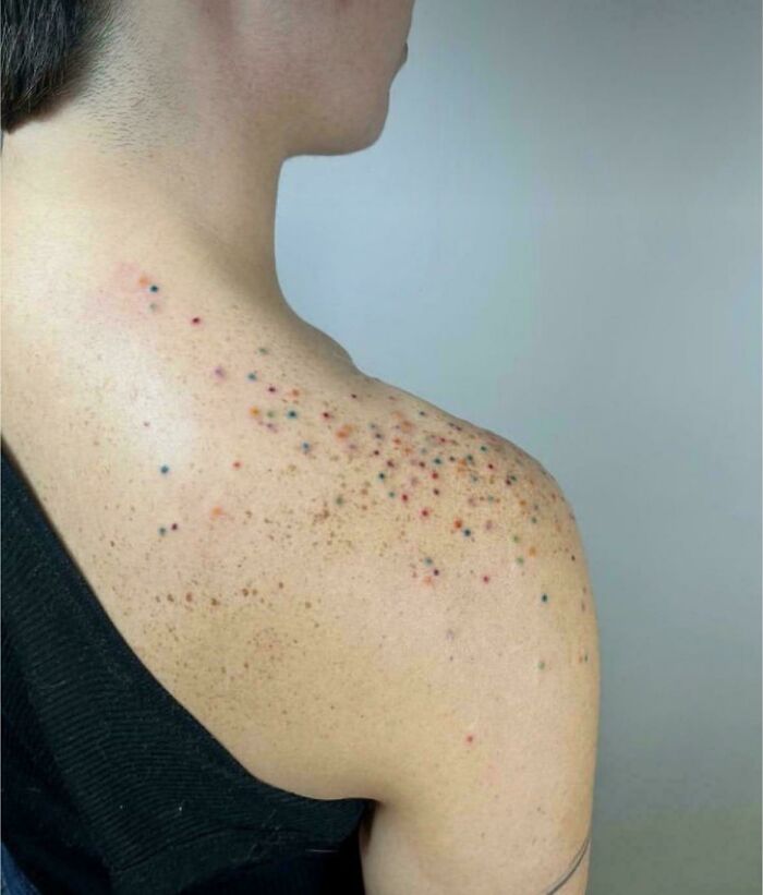 Poorly done tattoo on shoulder, showing a dotted pattern with random colors.