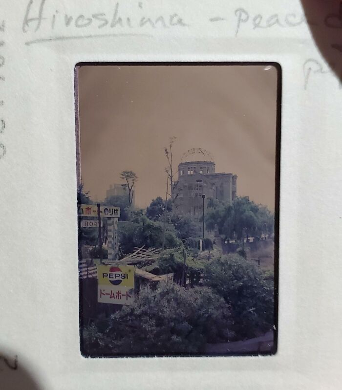 Historic Hiroshima dome site with 1973 signage, including a Pepsi ad, surrounded by greenery.