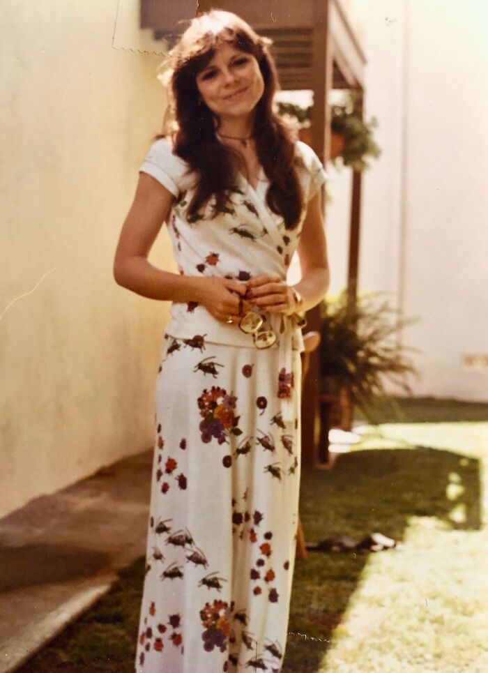 Smiling woman in floral dress standing outdoors, 1973, world-in-pictures theme.