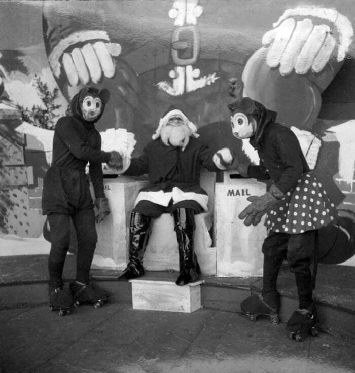 Creepy Santas with two figures in costumes, shaking hands, vintage black and white photo.