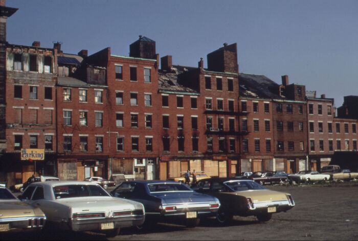 1973 urban street scene with vintage cars parked in front of old brick buildings.