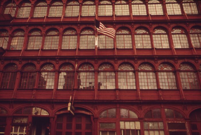 Historic red-brick building with arched windows from 1973, featuring an American flag in front.