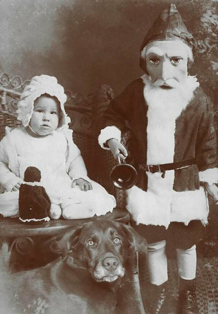 Vintage photo of a creepy Santa with a child and a dog, capturing an unsettling holiday scene.