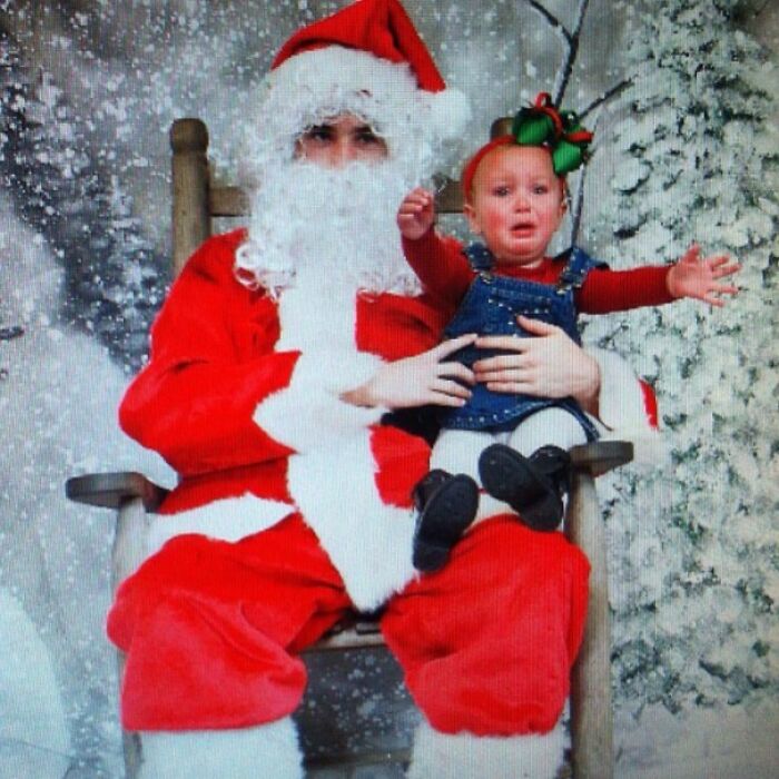 Creepy-Santas scene with a costumed Santa holding a crying child on a snowy backdrop.