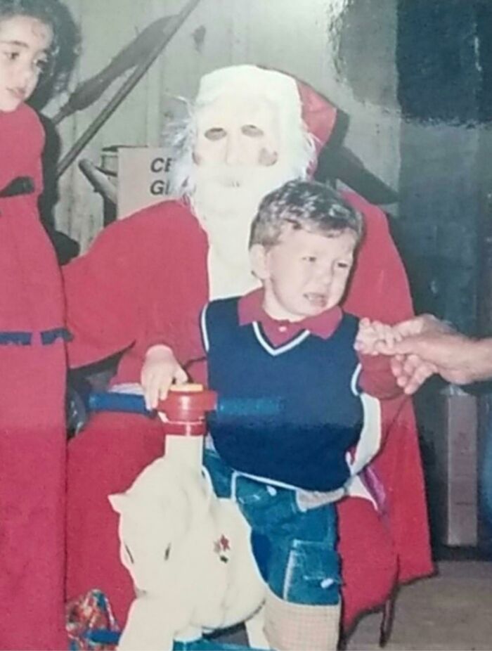 A child crying while sitting on the lap of a figure dressed as a Santa, exemplifying a creepy Santa encounter.