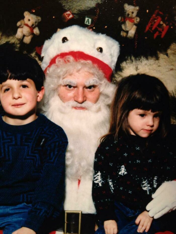 Two kids sitting with a serious-looking Santa, capturing the essence of Creepy-Santas holiday photos.