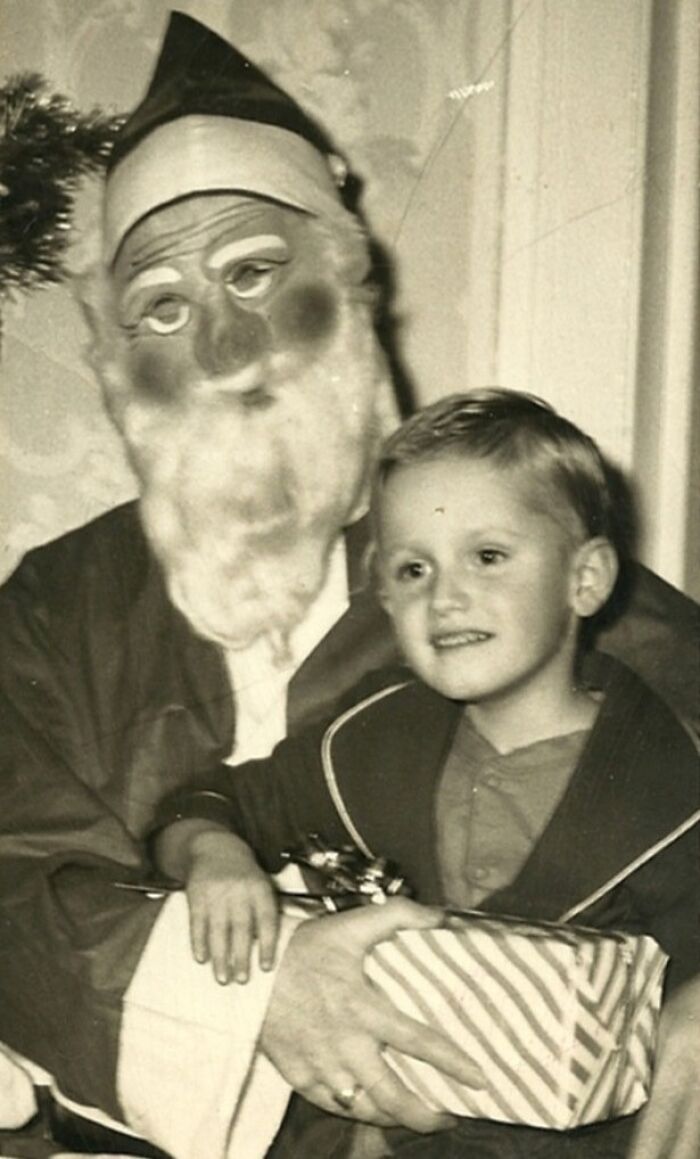 Child sitting on a Creepy-Santa's lap, holding a wrapped gift.