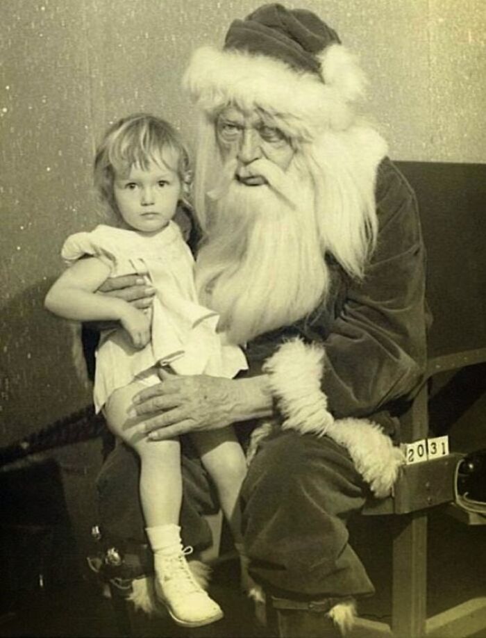 Child on the lap of a vintage Santa Claus, conveying a spooky atmosphere.