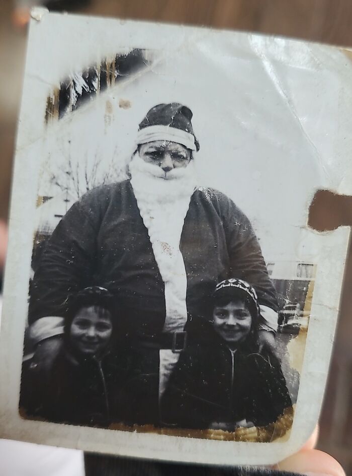 A vintage creepy Santa with two smiling children in an old black-and-white photo.