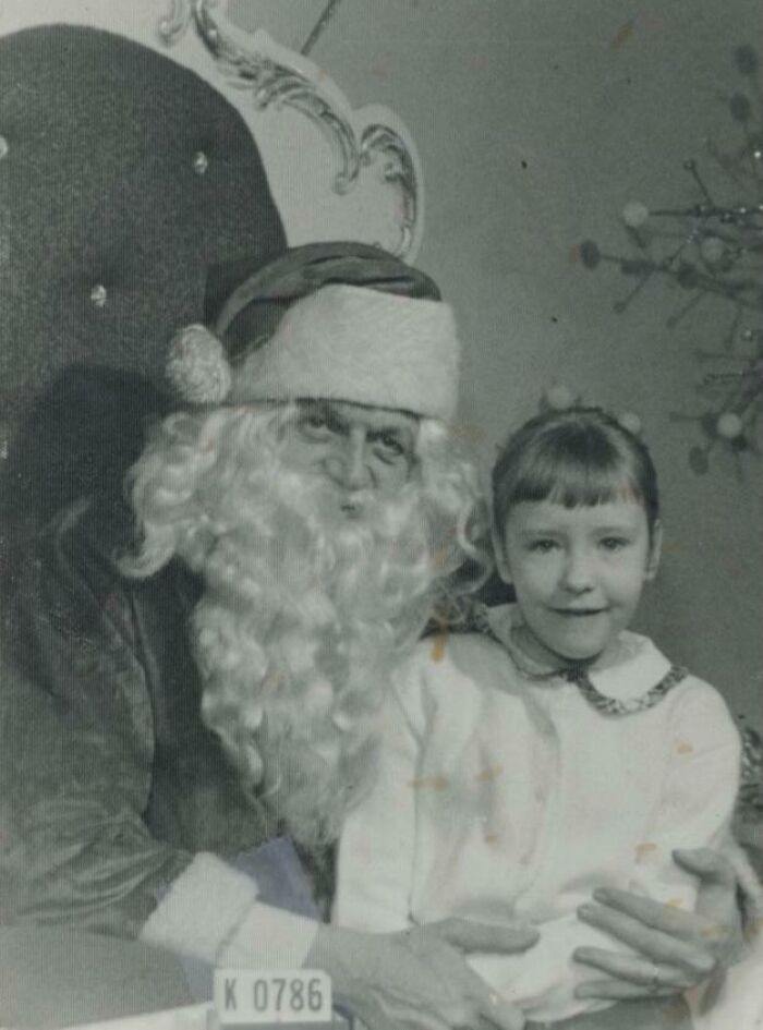 Creepy Santa with a child sitting on his lap, vintage black and white photo.