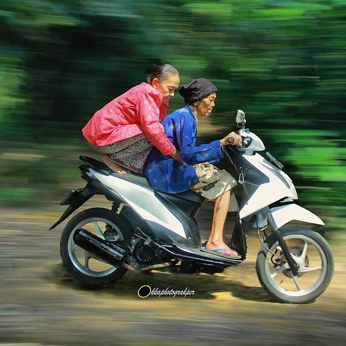 Elderly women on a scooter in Indonesia, showcasing captivating simple life moments.