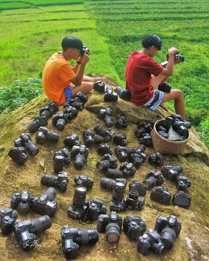 Indonesian photographer captures two boys with cameras on a hill, surrounded by greenery.