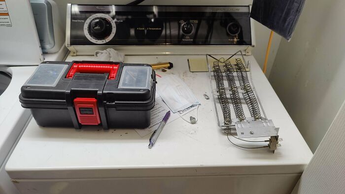 Toolbox and dryer repair parts on a washing machine, illustrating the rewarding job of being a dad.