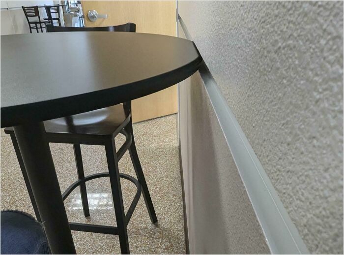 Satisfying perfect fit of a round table flush against the wall in a minimal room setting.