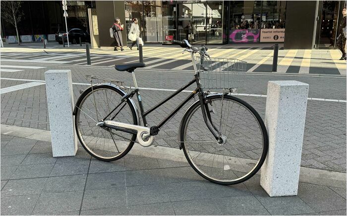 Bike parked between two posts, showcasing a satisfying perfect fit on a city sidewalk.