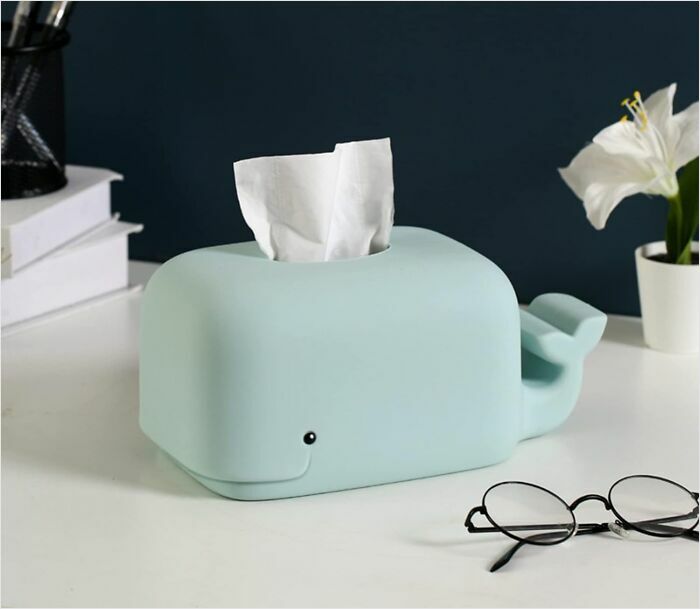 Whale-shaped tissue box on desk with books, glasses, and a white flower.