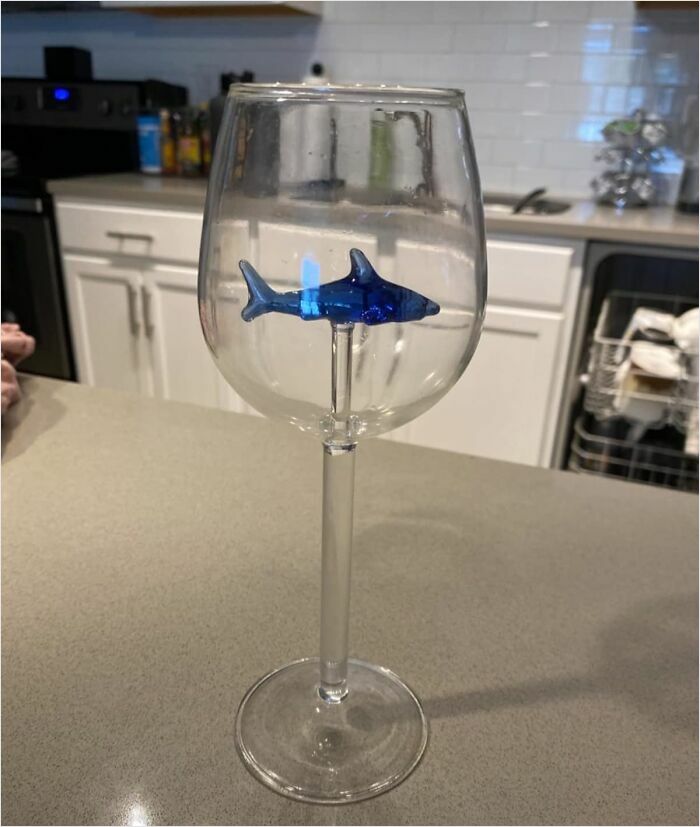 Wine glass with a blue shark inside, on a kitchen counter, showcasing a unique design among coolest things to covet.