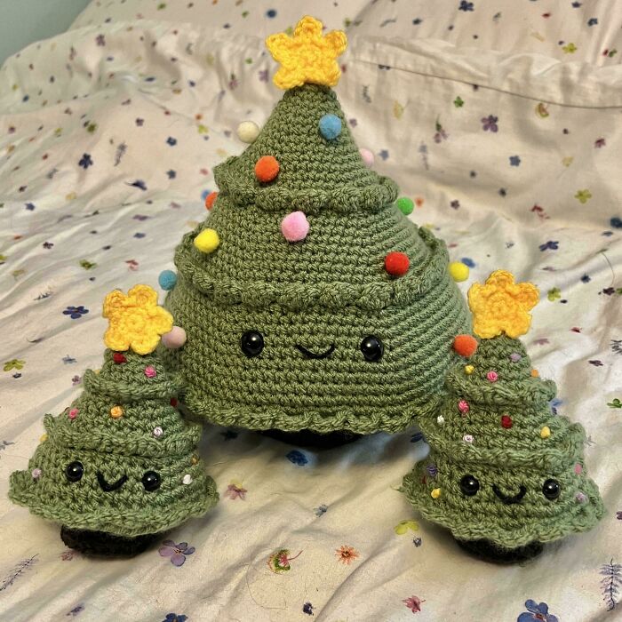Crochet Christmas tree projects with colorful pom-poms and yellow star toppers, showcasing proud handmade crochet crafts.