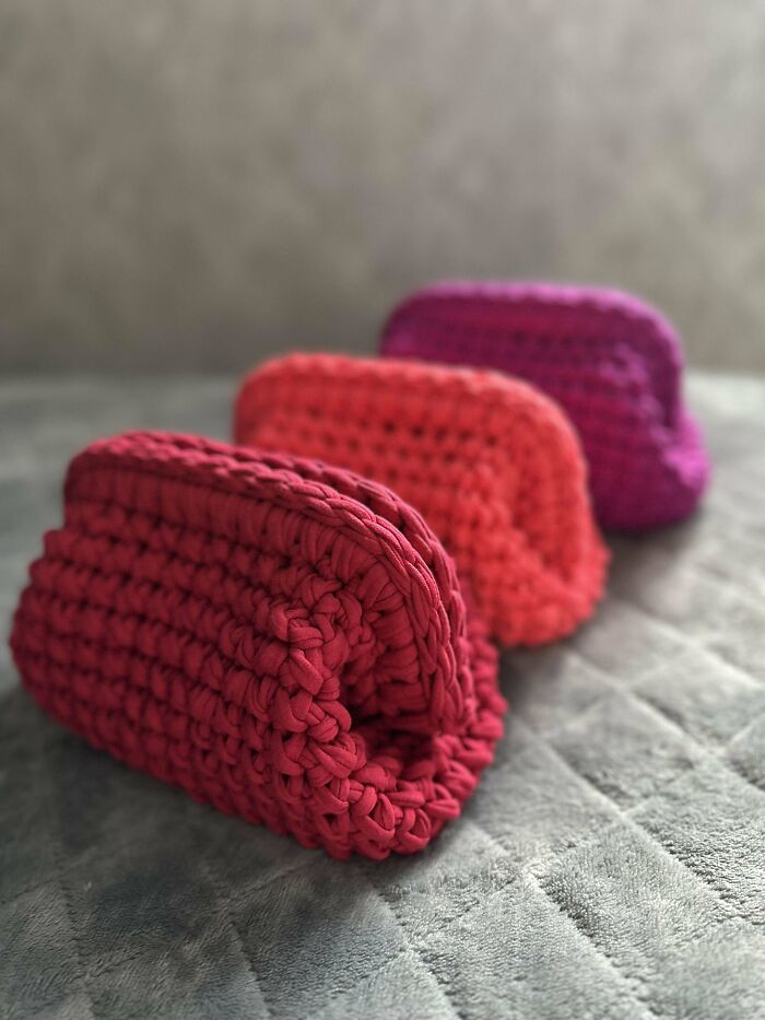 Three colorful crochet pouches in red, orange, and purple, showcasing proud crochet enthusiasts' handmade projects.