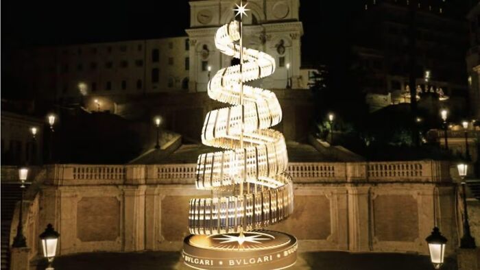 Illuminated spiral Christmas tree in a city square, showcasing unique holiday decor from around the globe.