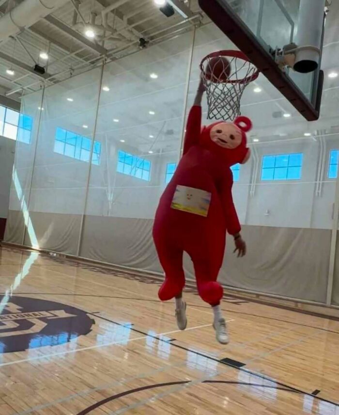 Person in a red costume dunking a basketball inside a gym, showcasing weird side of the internet humor.