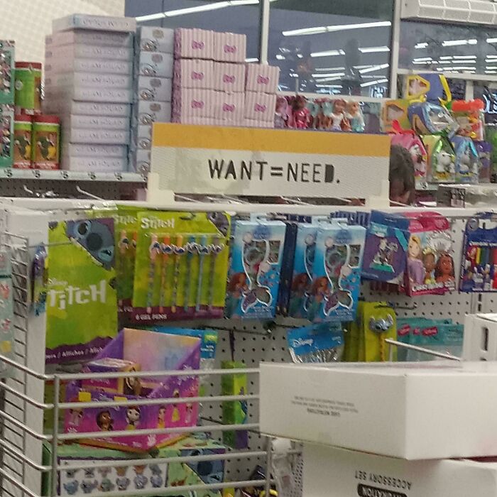 Store shelf with toys and ironic "Want = Need" sign, highlighting consumerism.