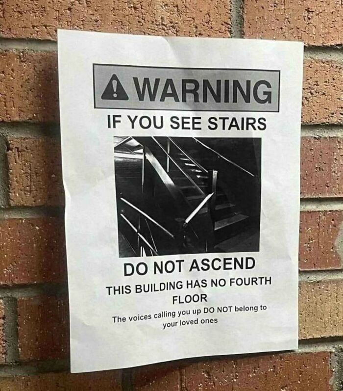 Warning sign on a brick wall advising against ascending nonexistent stairs, emphasizing weirdness and surreal humor.