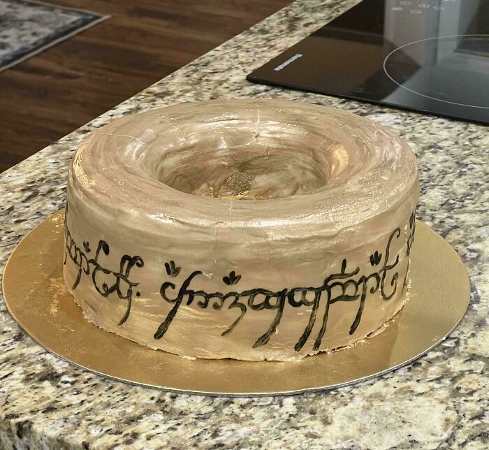 A creative cake resembling the One Ring from Lord of the Rings, featuring intricate black script details.