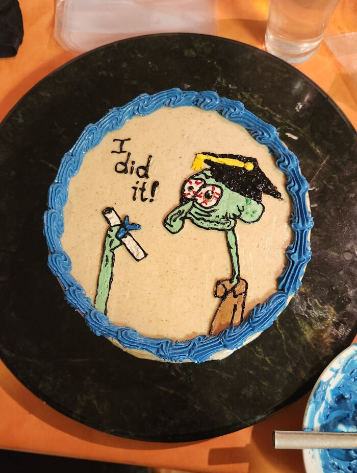 Decorative cake featuring a cartoon character in a graduation cap, celebrating with the text "I did it!" in icing.