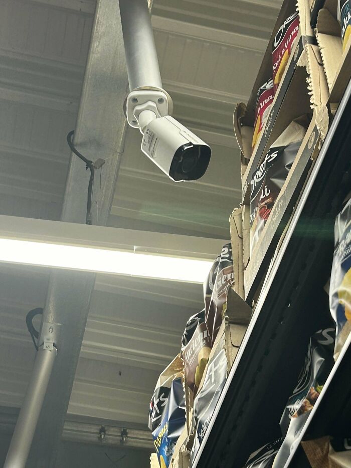 Security camera overlooking shelves of snack bags in a store, highlighting everyday surveillance.