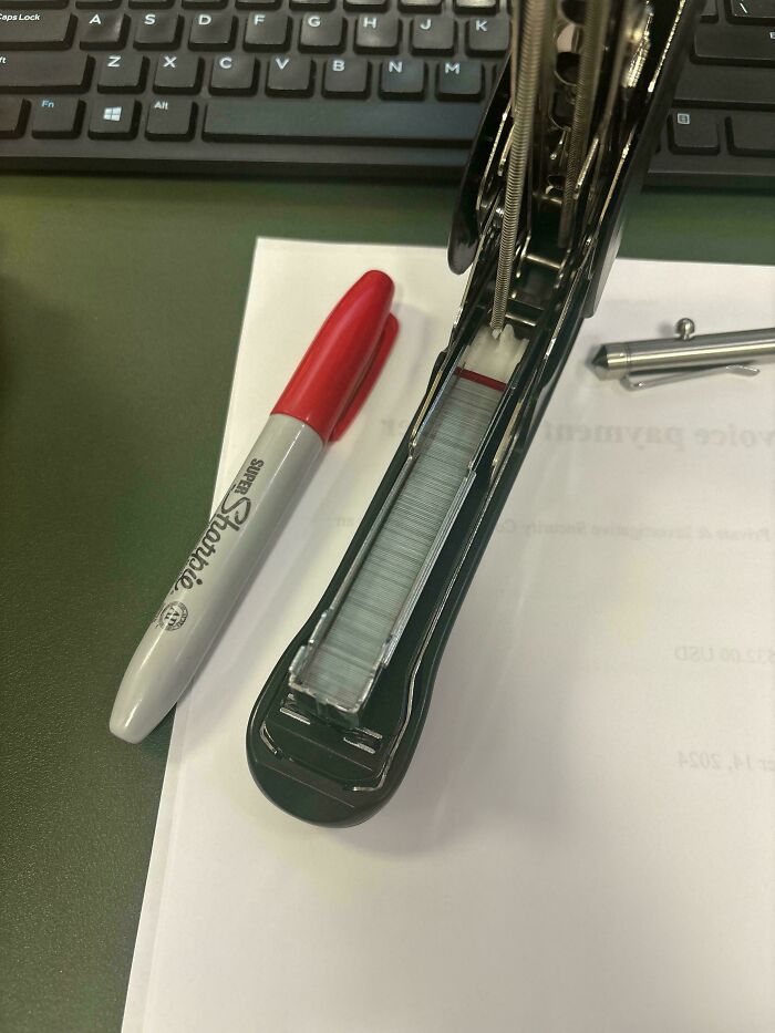 Sharpie and stapler on a desk with a keyboard; mundane office items, nothing interesting about them.