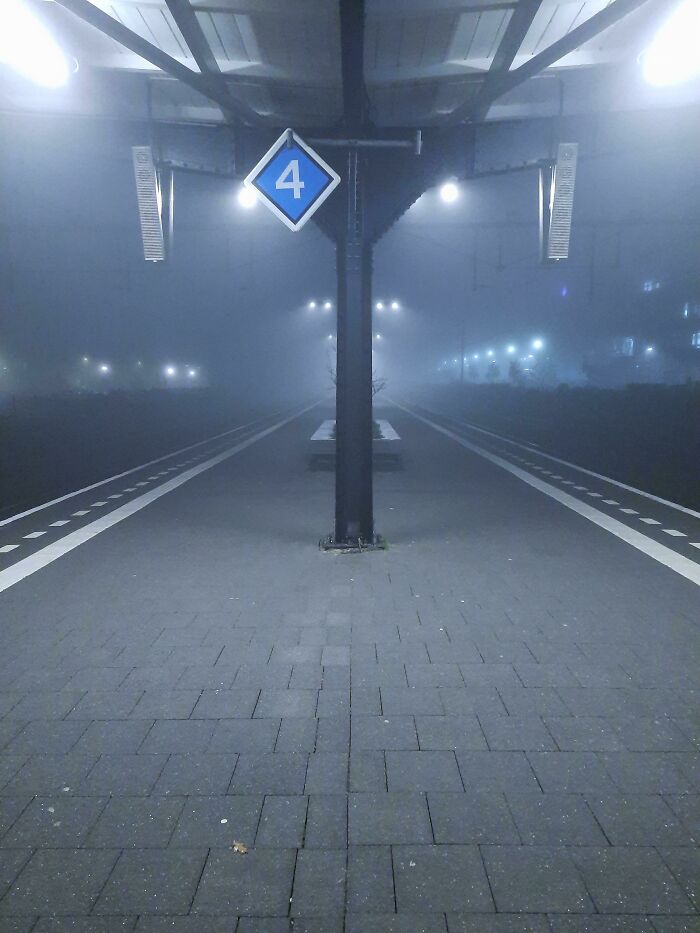 Foggy train station platform resembling a videogame scene with glowing lights and a "4" sign overhead.